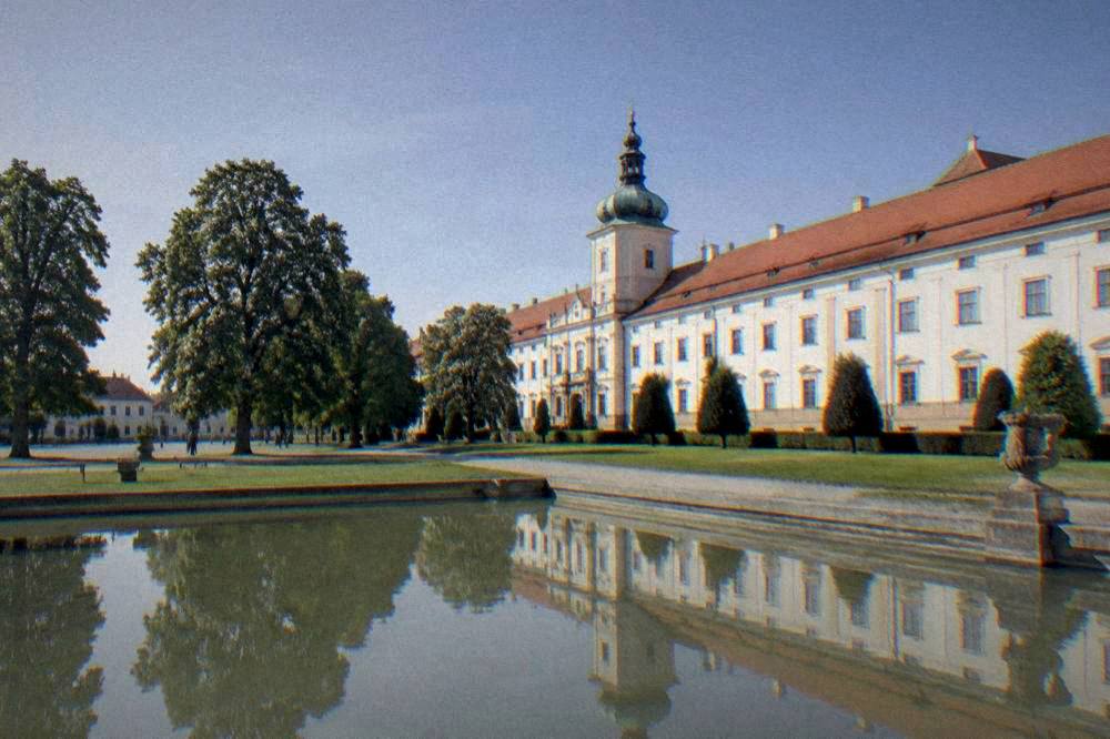 Evening light over a Moravian palace garden with long shadows across a lawn