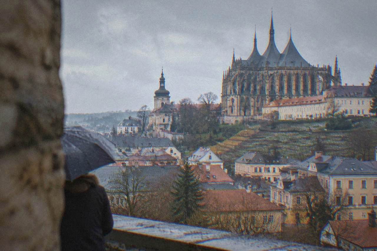 View over the rooftops and church spires of a historic Czech town under an afternoon sky