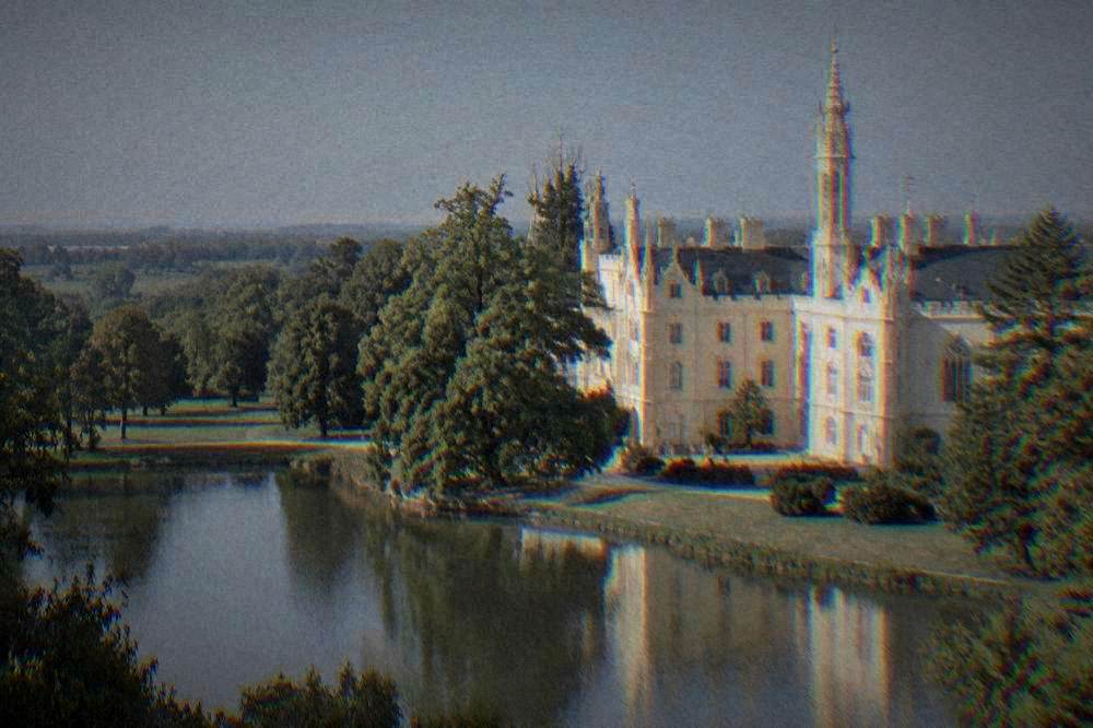 Pale chateau facade beside a pond and trees