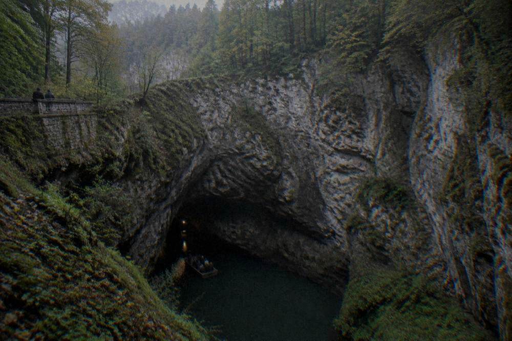 An underground boat on a dim river inside a limestone cave passage