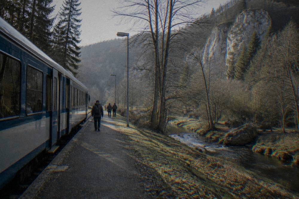 A regional train standing at a small Czech station platform surrounded by trees