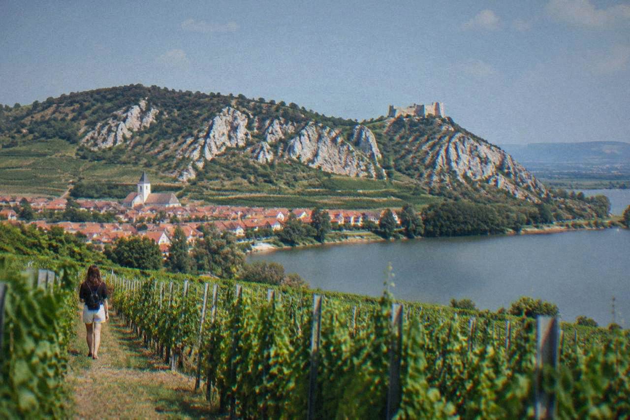 White limestone hills rising above vineyards and a village with terracotta roofs under a blue sky