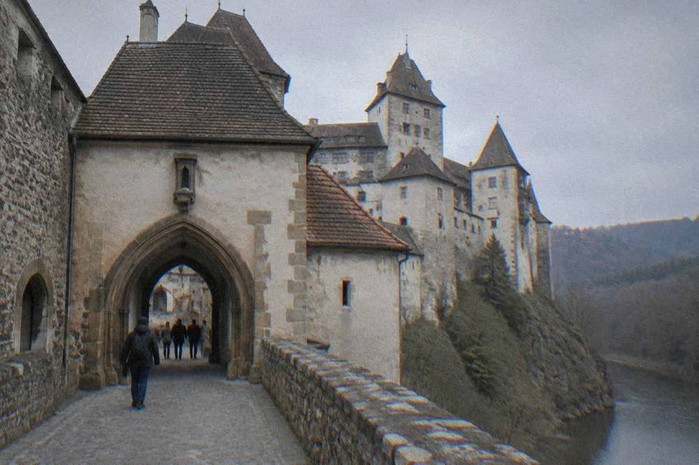 A Gothic castle gateway with stone arches and a ticket entrance