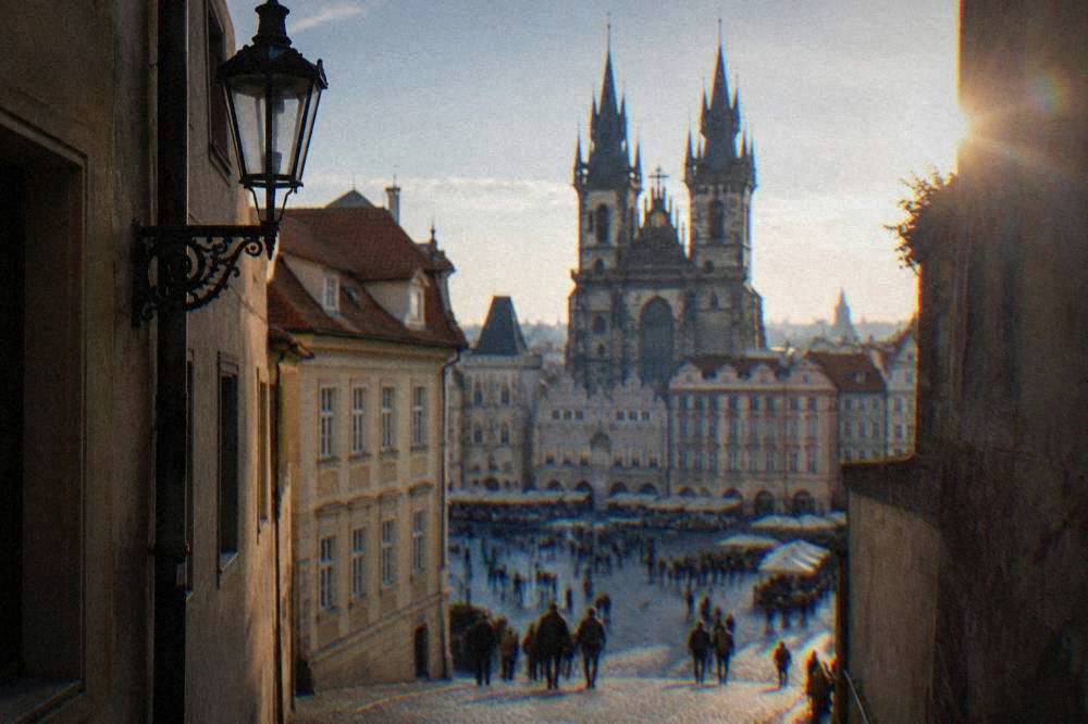 A narrow old European street opening onto a square with church towers