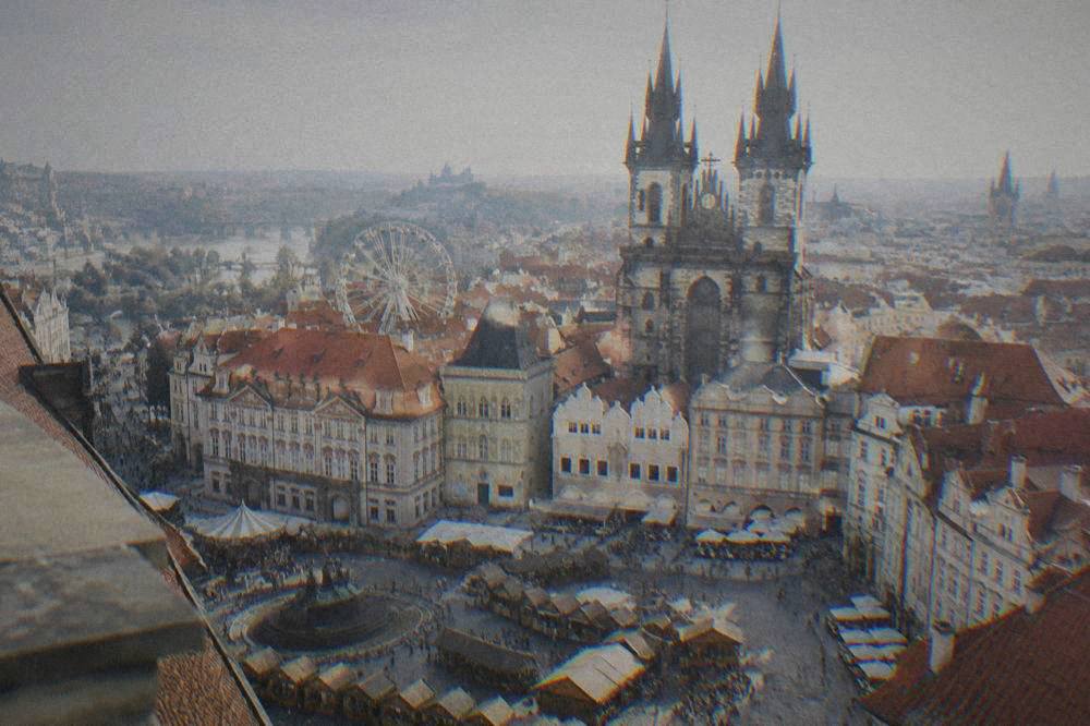 A city square with wooden market stalls and a ferris wheel in the background