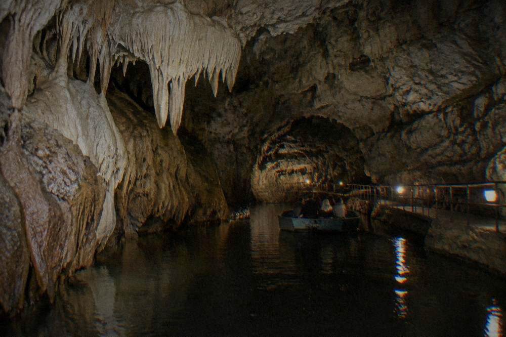A deep open limestone gorge with forested cliffs and visitors at a viewing platform on the rim