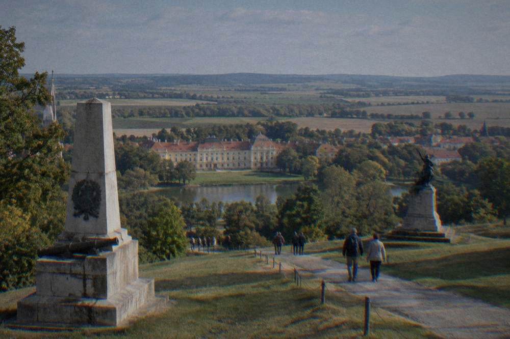 Visitors walking a path between battlefield monuments near Slavkov u Brna
