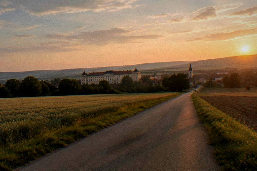 A quiet country road between fields leading toward Slavkov u Brna at sunset