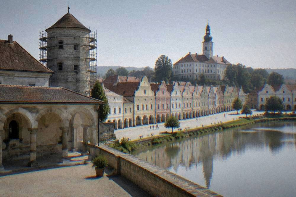 A castle courtyard with a stone arcade and a round tower under repair scaffolding