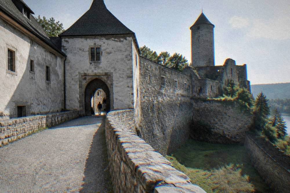 A stone gatehouse and courtyard of an old castle seen from below
