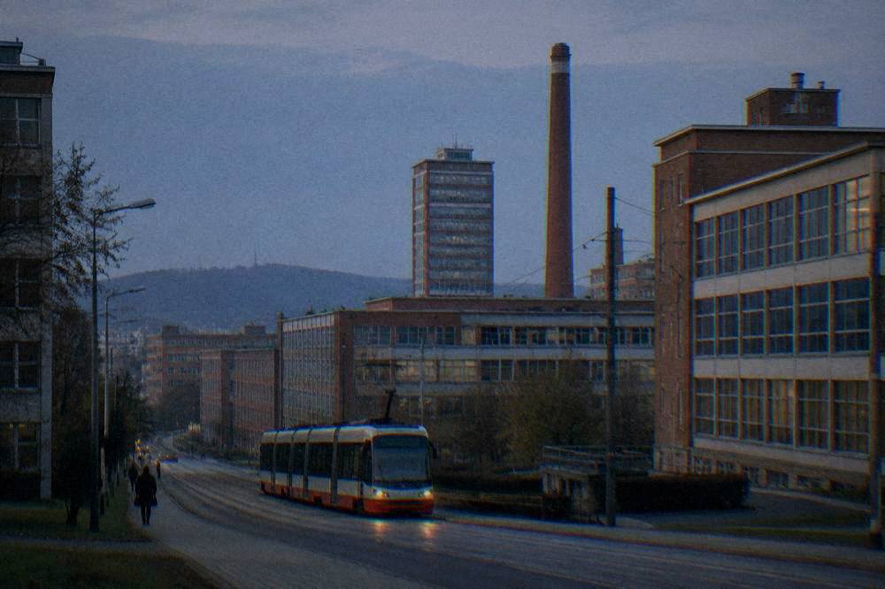 A tram passing modernist buildings on a city street in daylight