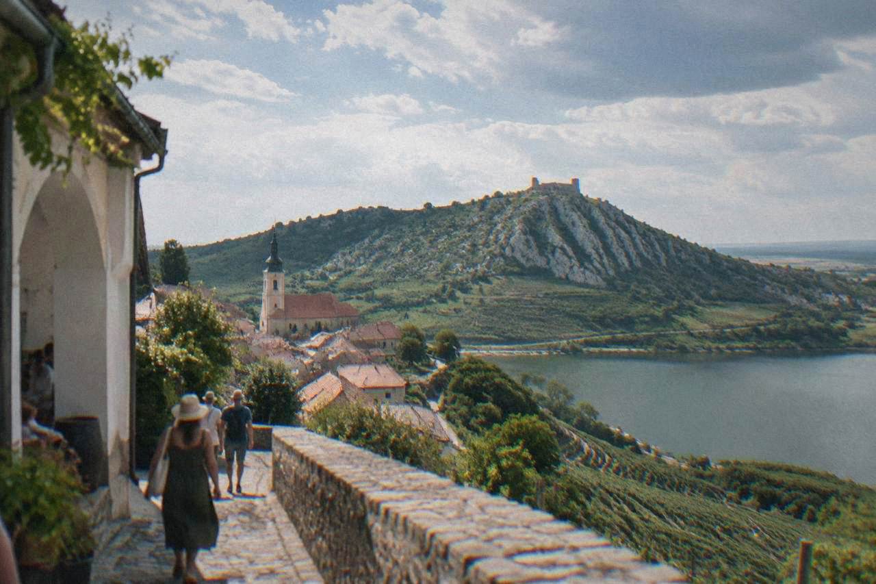 A South Moravian hilltop town with a church tower and terraced vineyards under a summer sky