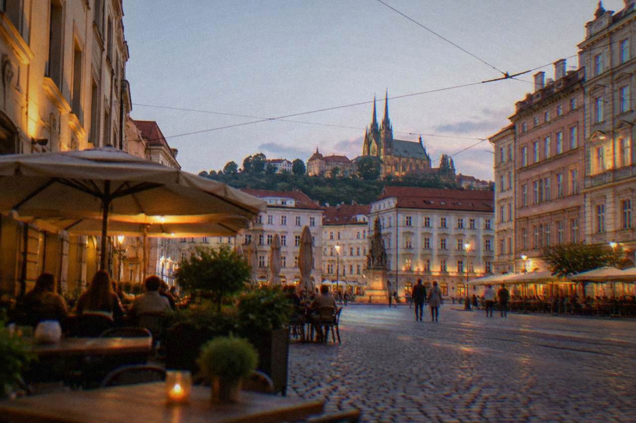 Evening view over a Brno square with outdoor tables and lit facades