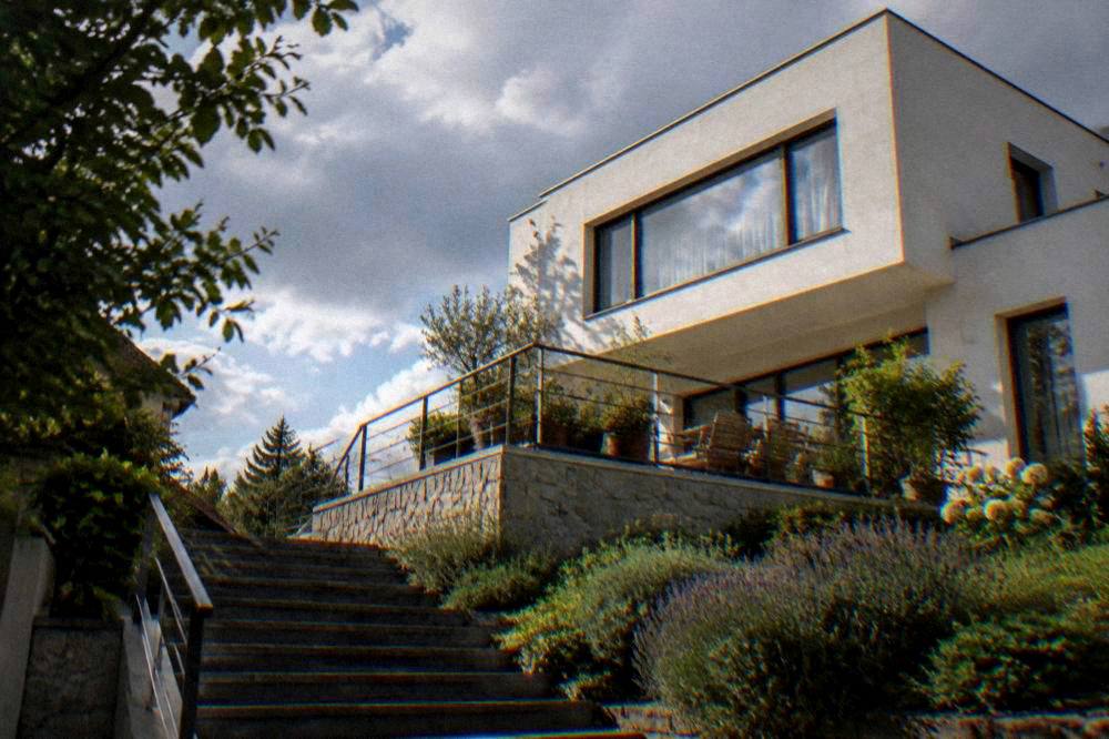 A modernist white villa with a garden terrace photographed from below