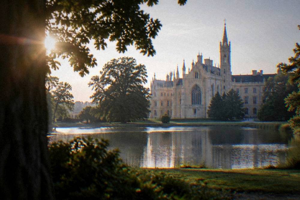 Chateau with a tall ornate facade beside a lake and parkland in the Lednice-Valtice landscape