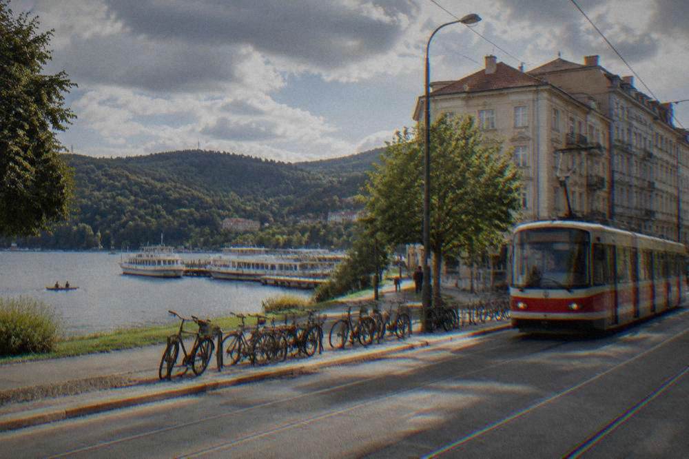 A tram passing a row of parked bicycles on a city street with older apartment buildings