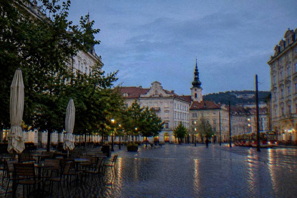 Empty café chairs on a wet cobblestone square after rain