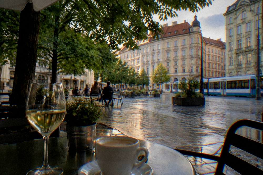 Glass of white wine and a coffee cup on a café table in the evening
