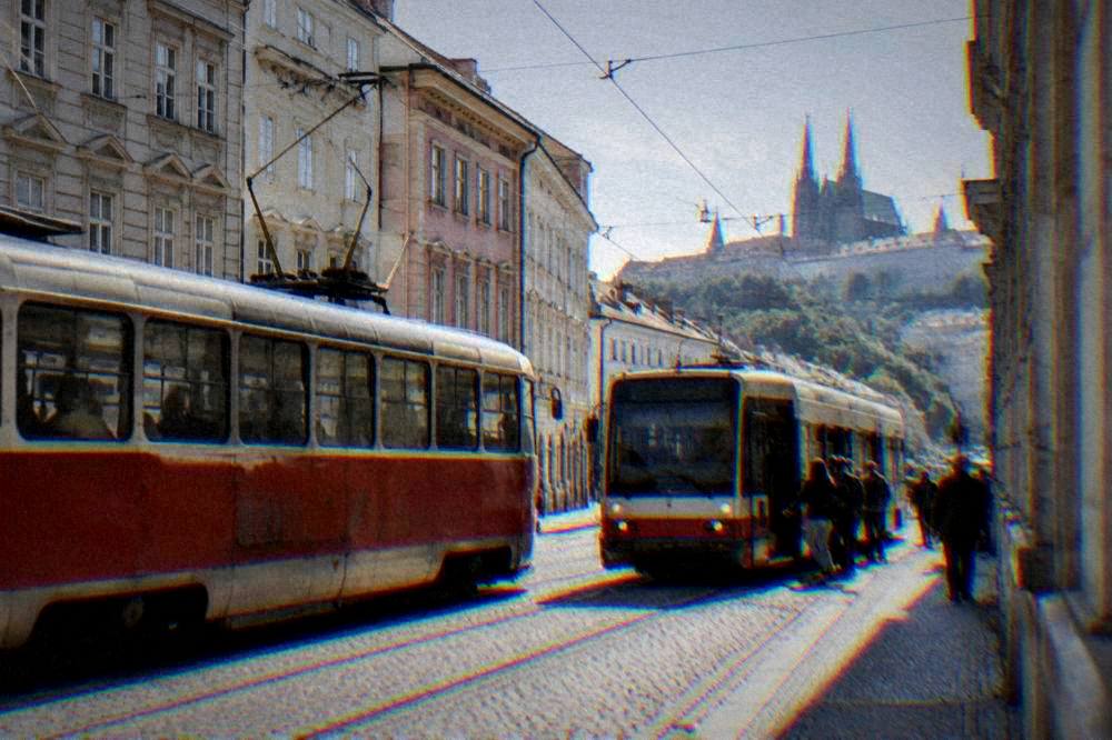 Trams passing each other on a city street in Brno with passengers boarding