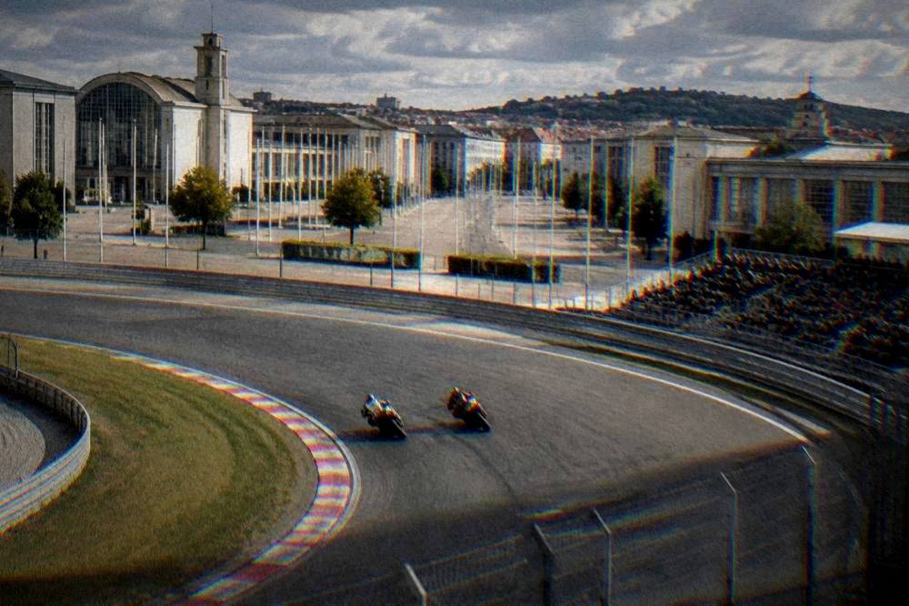 Motorcycles racing side by side through a sweeping track corner with grandstands in the background