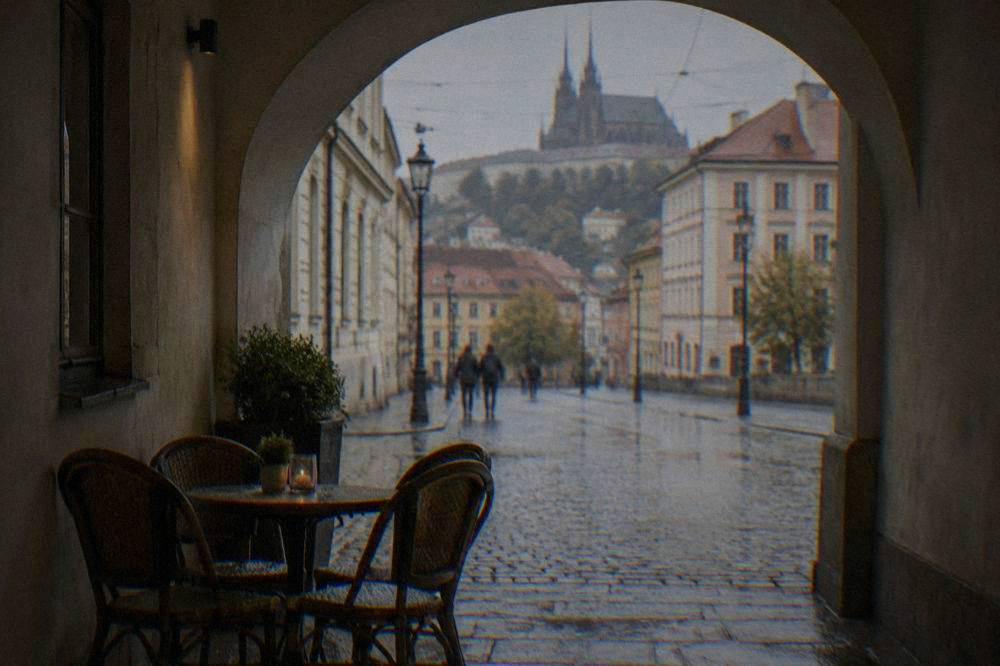An arched courtyard passage in Brno with a cafe table under old vaulting