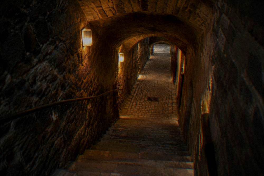A stone cellar corridor lit by warm lamps under Brno
