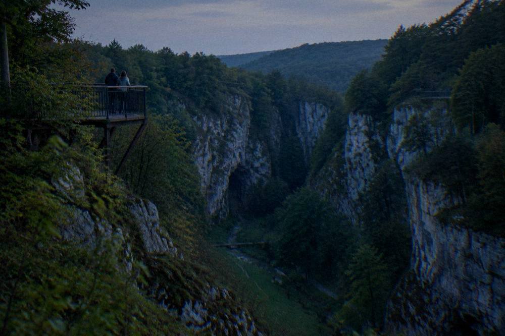 A forested limestone gorge with a deep abyss and viewing platforms in the Moravian Karst