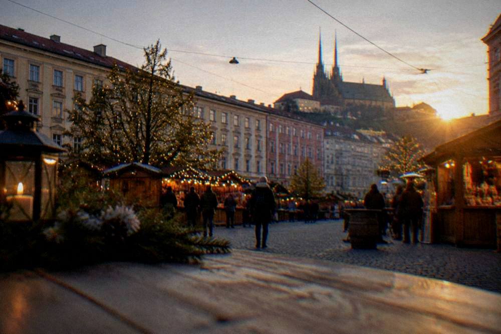 A market square in Brno at dusk with wooden stalls and illuminated trees