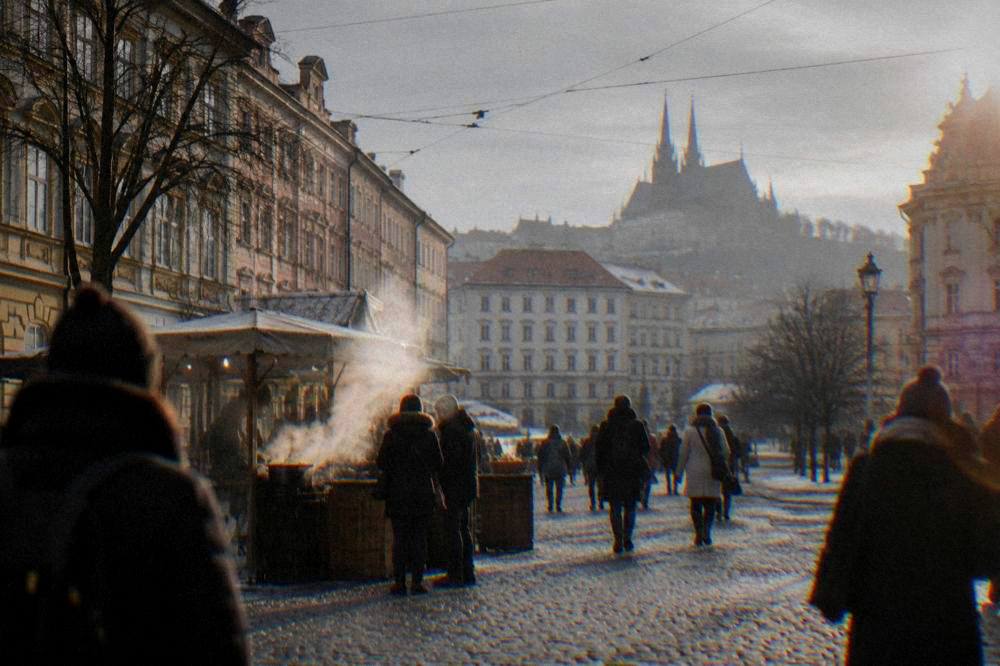 People walking across a Brno square with steam rising from a food stall