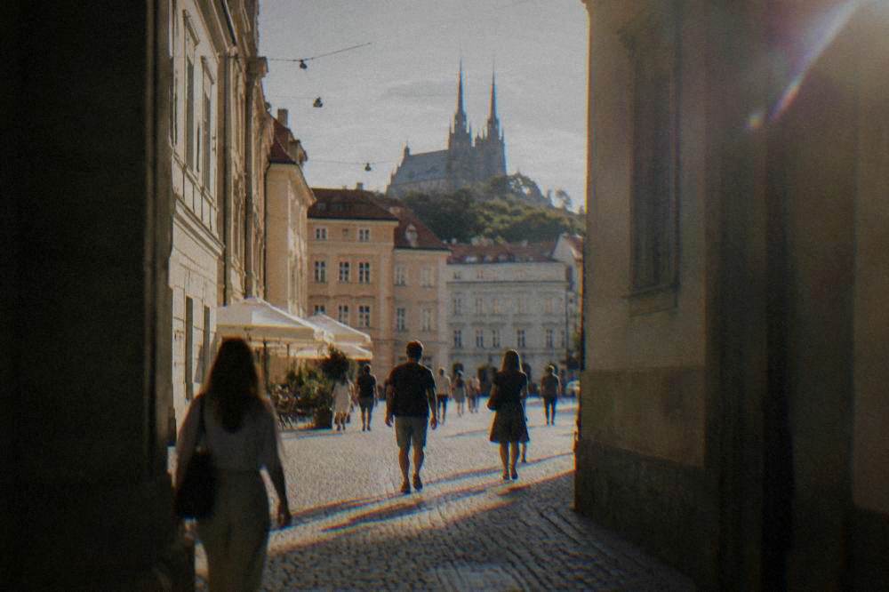 Tourists walking through a historic passage in Brno's city centre on a sunny day