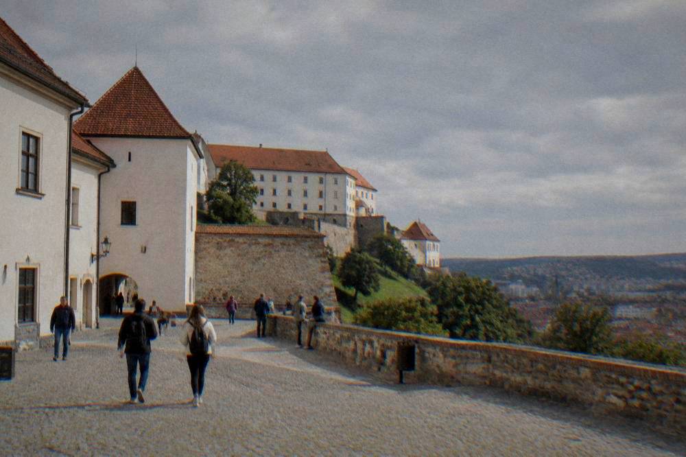 Sunlit courtyard of Špilberk Castle with visitors walking
