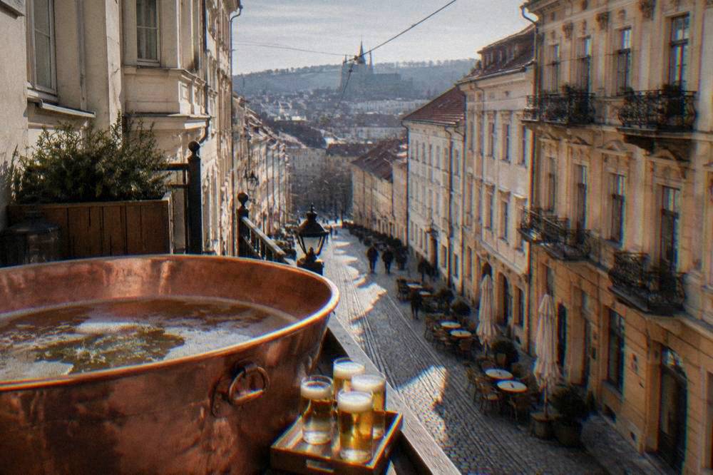 A copper tub of beer spa bath with glasses of pale lager on a wooden tray beside it