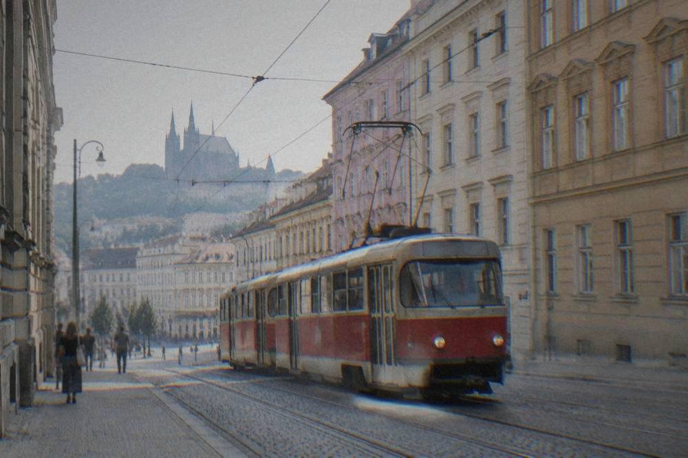 A red Brno tram passing older apartment buildings on a street in the city centre
