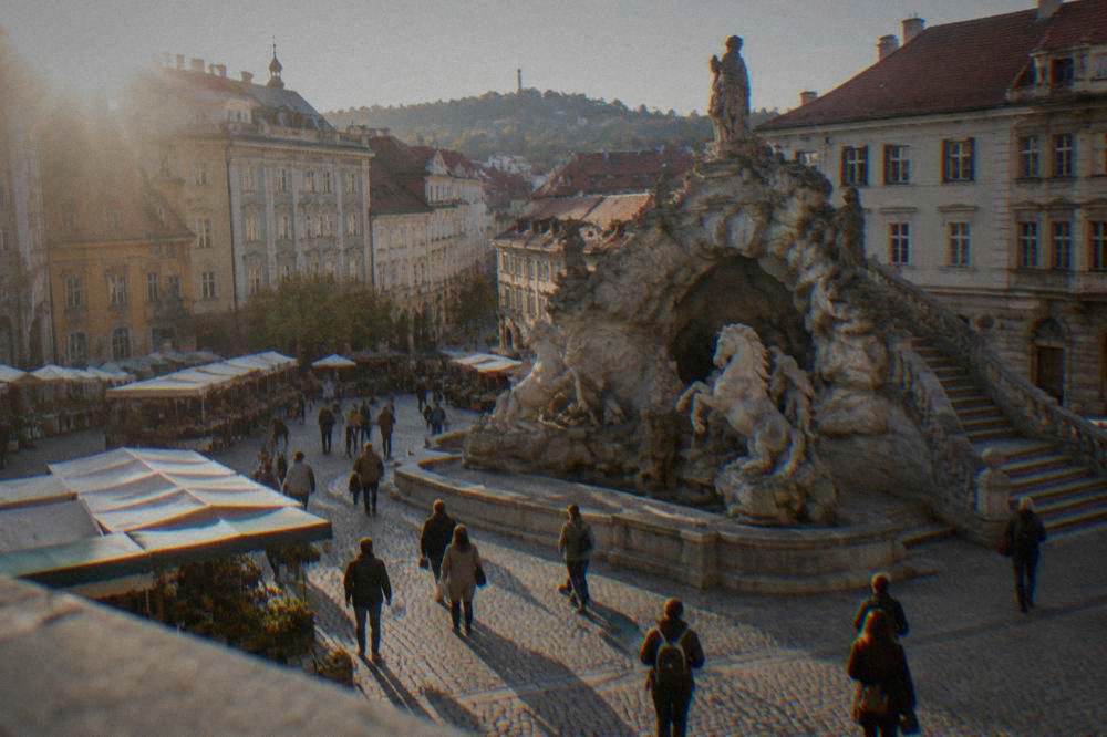 Visitors walking through the Cabbage Market in Brno beside market stalls and the historic Parnas fountain
