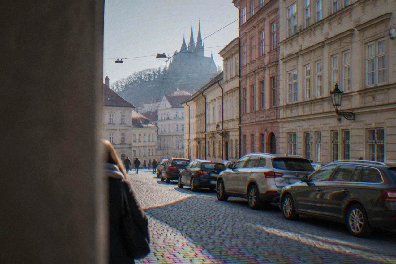 Cars parked along a street in central Brno with historic buildings behind them