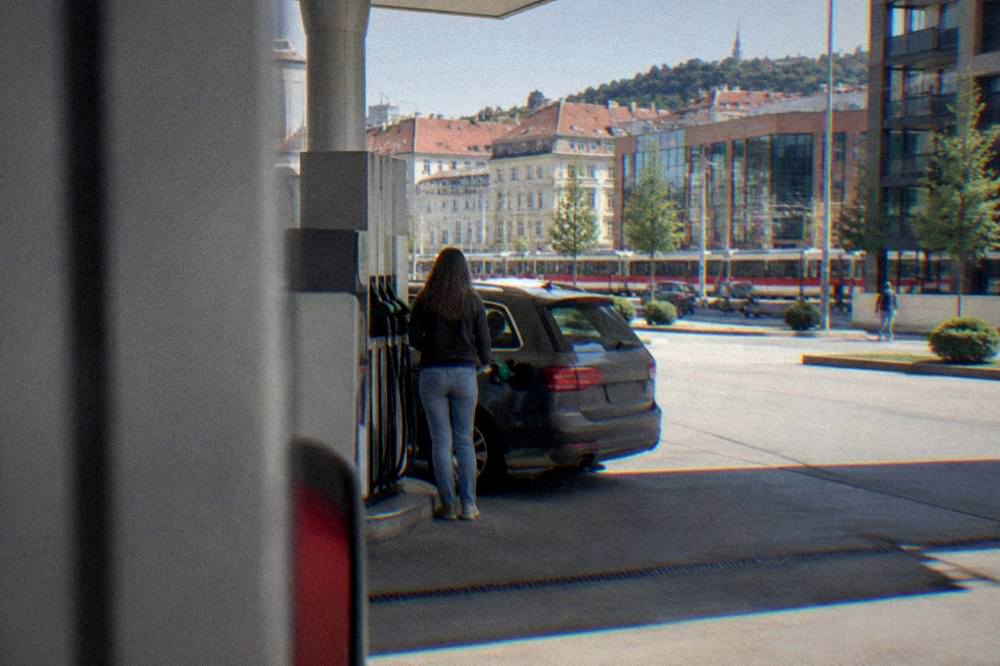 A petrol station forecourt with a car filling up on a sunny day