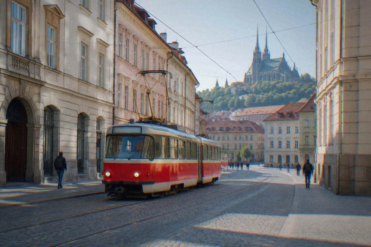 A red and white tram moving along a street in central Brno