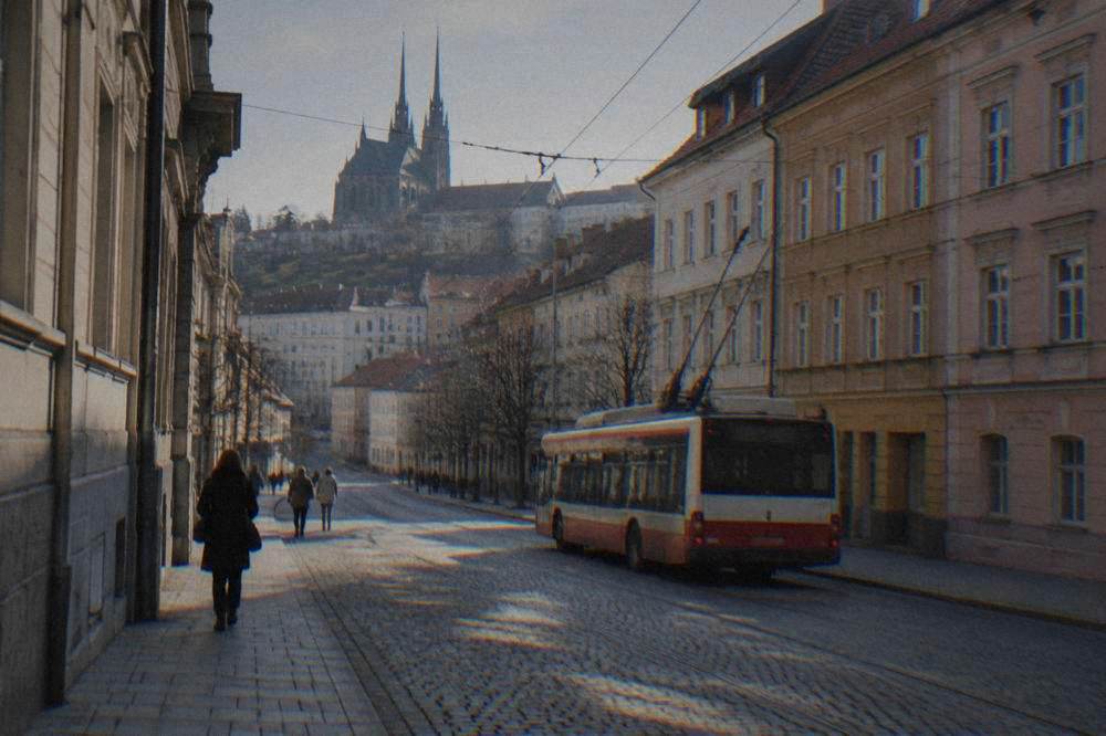 A trolleybus passing colourful buildings on a Brno street