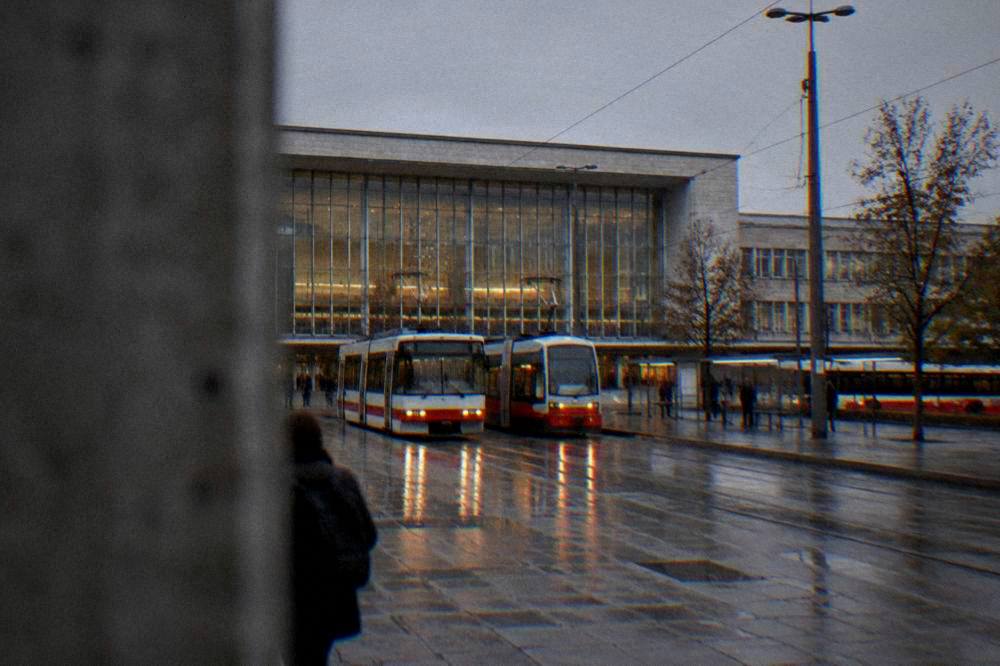 Two trams side by side outside Brno main railway station at dusk