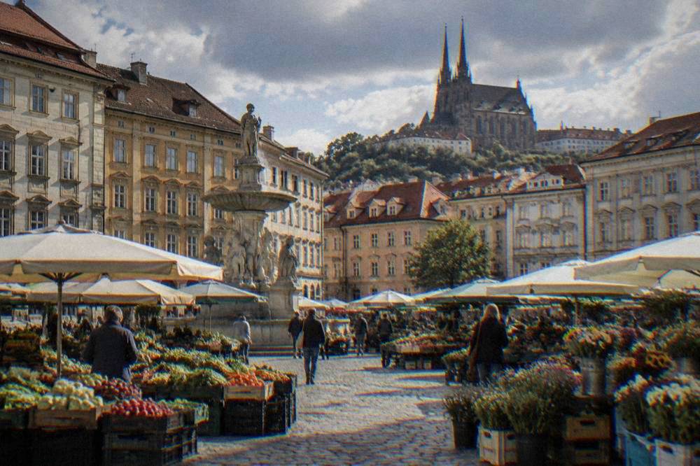 Fresh produce and flower stalls on a cobbled square with historic buildings behind