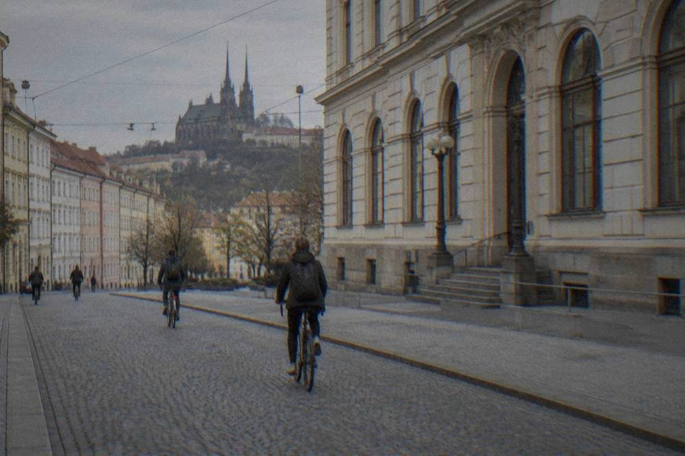 A university building facade in Brno with cyclists passing below