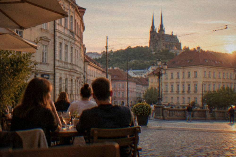 People gathered at an outdoor table on a Brno square in the evening