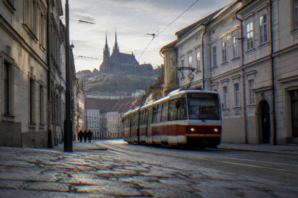 A tram moving along a Brno street in the early evening