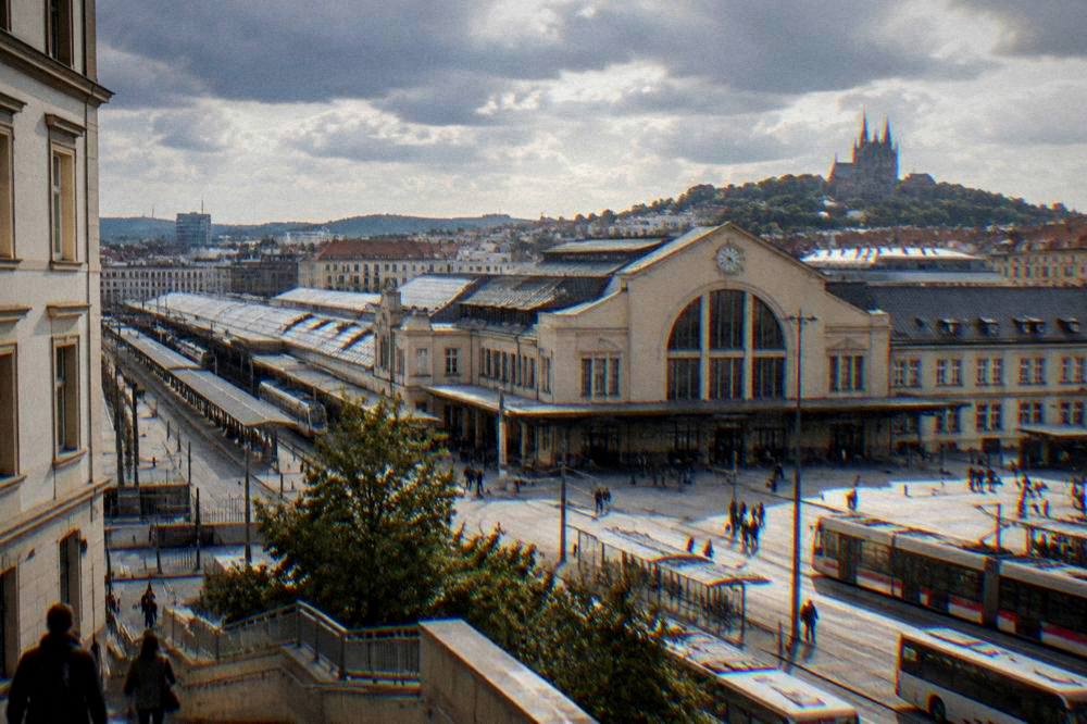 The exterior of Brno main station with the station sign and buses at the forecourt at dusk