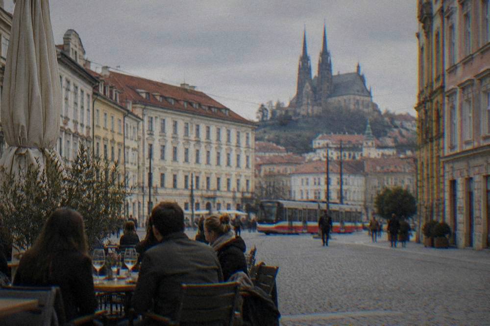 Diners at an outdoor table with wine glasses in a Moravian square