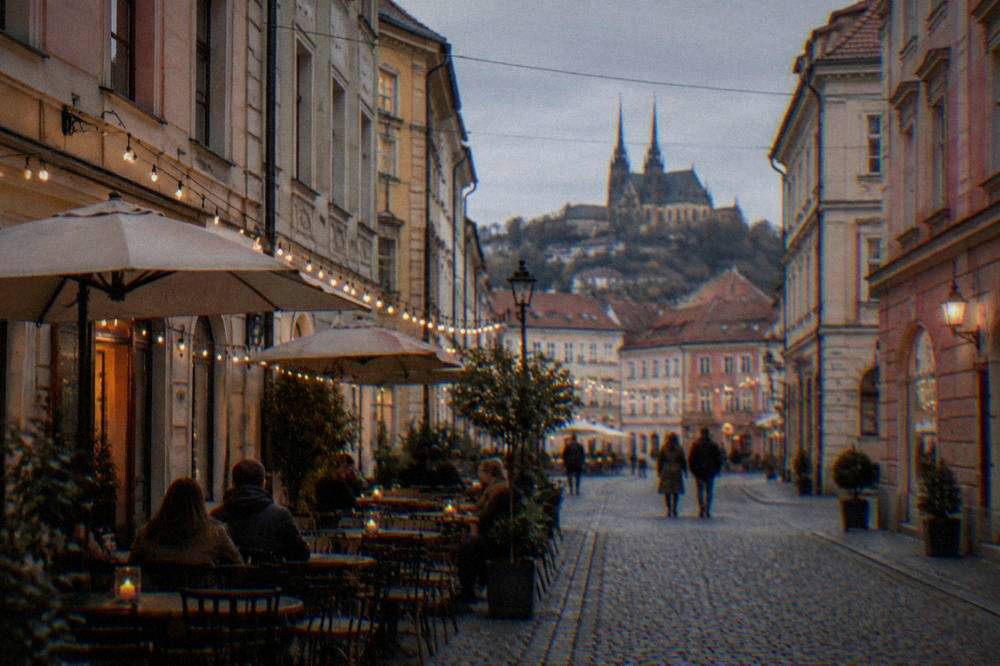 An evening street with cafe tables and string lights between old buildings in a city centre