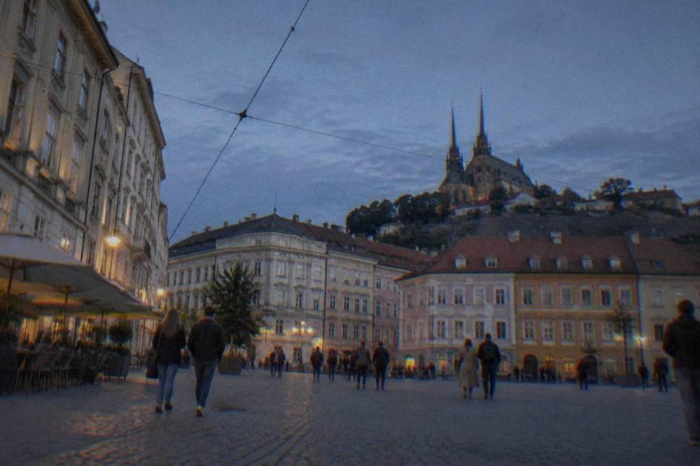 People strolling across a spacious historic square lined with colourful facades in Brno
