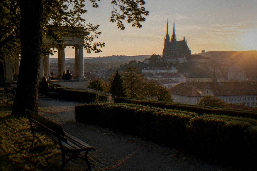 Twin-spired cathedral on a hill overlooking city rooftops at golden hour