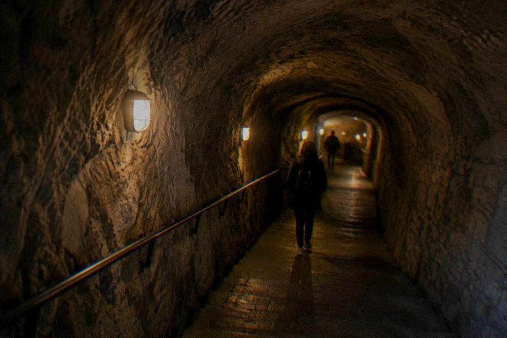 Tunnel corridor inside an underground attraction in Brno lit by warm lamps