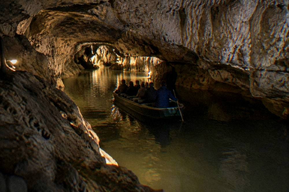 Boat on an underground river inside a lit cave in the Moravian Karst